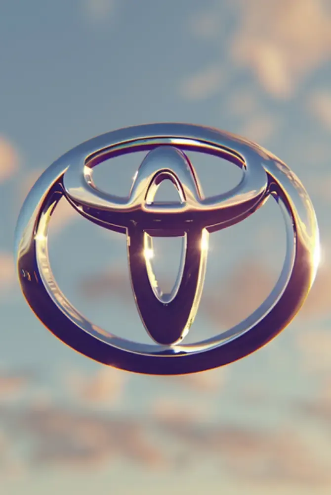 Toyota logo in front of a soft cloudy sky, lit by the sunset